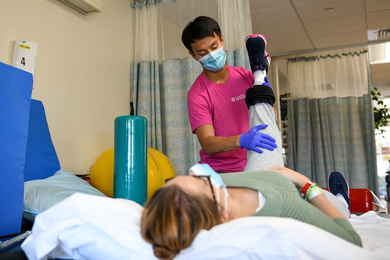 Physical therapist helps patient move through various stretches and strengthening exercises