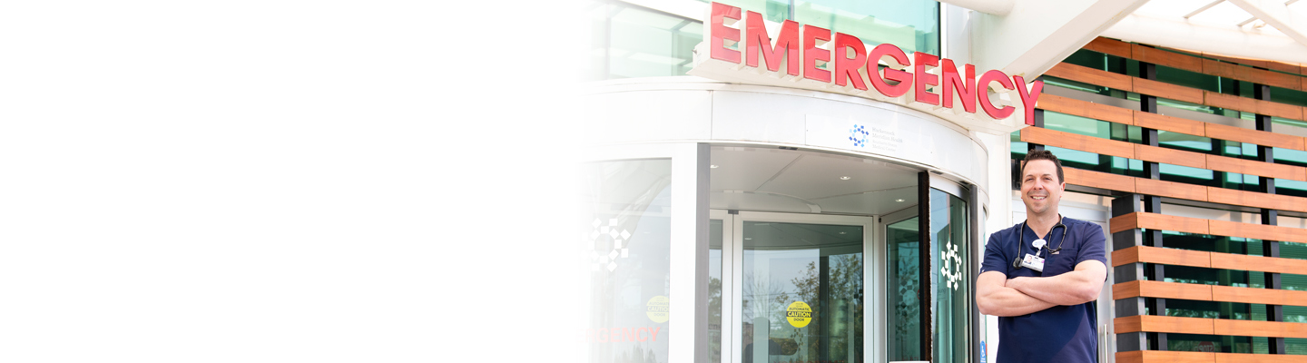 A physician standing outside of the emergency services departmental building
