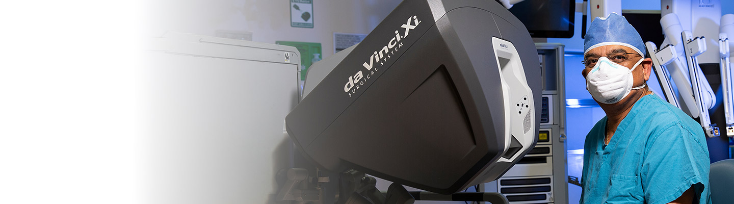 ENT surgeon in the OR sitting in front of da Vinci surgical system machine