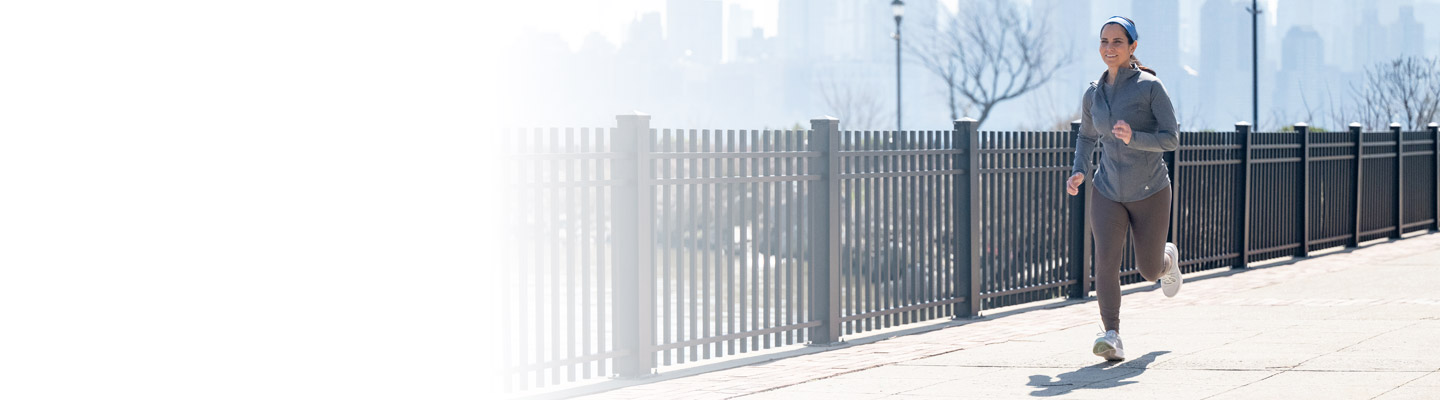 women running outside next to a fence