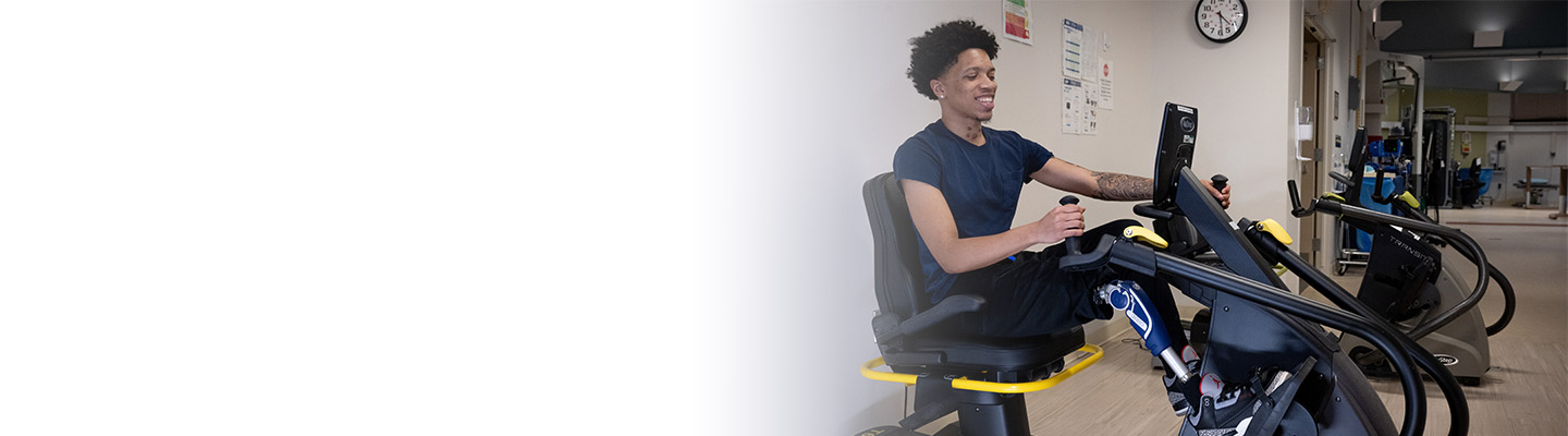 Physical therapist standing with a patient on an exercise machine