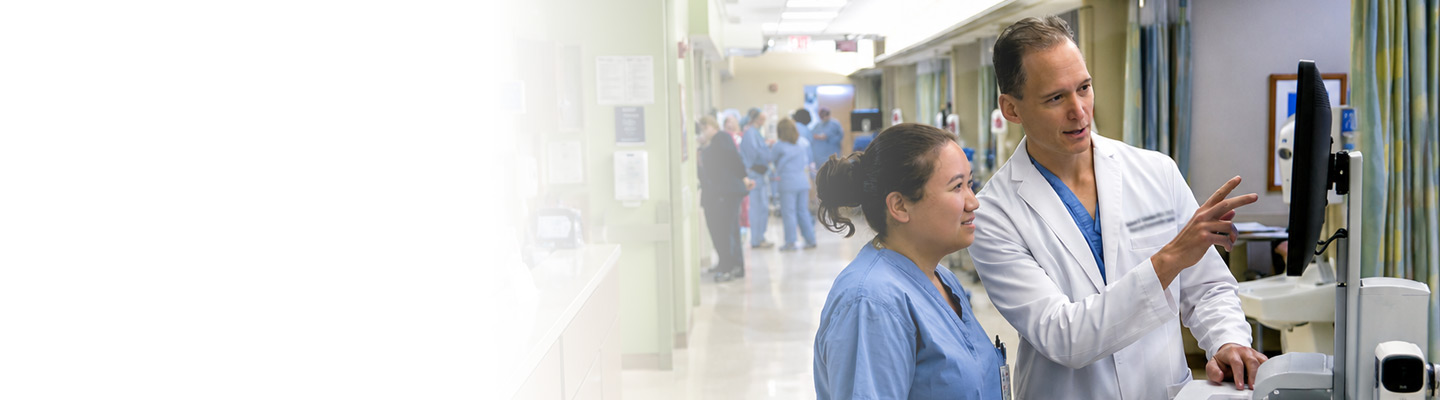 Healthcare professionals collaborating at a hospital computer station.