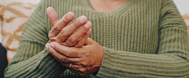 Woman holding her hand, aching from arthritis, possibly from COVID