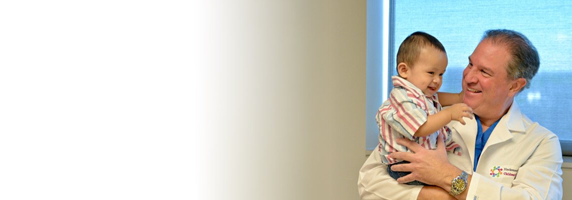 Pediatrician and holding a smiling young patient in his arms