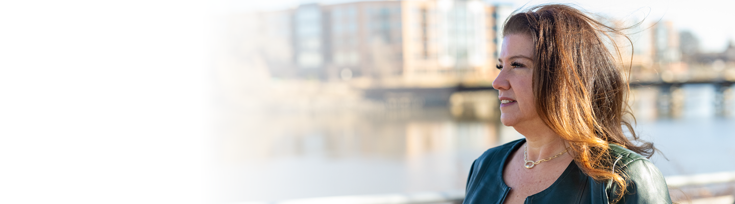 Women with green shirt smiling in front of a city landscape