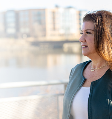 Women with green shirt smiling in front of a city landscape