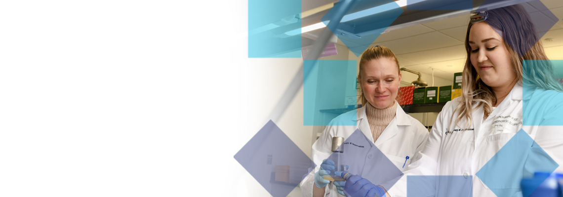 Two women wearing lab coats looking looking down at a table