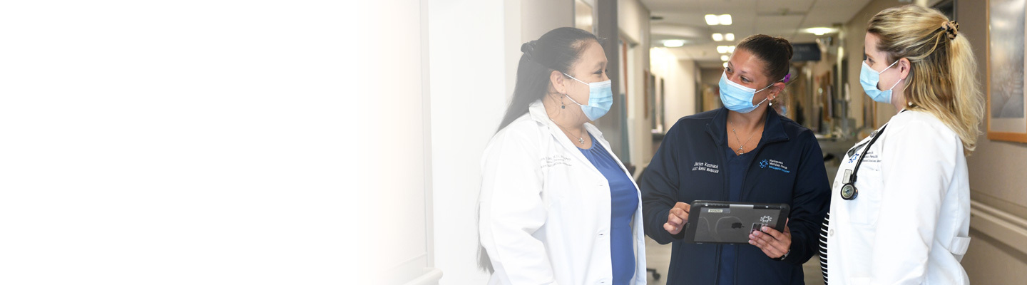three female healthcare workers talking in a hallway