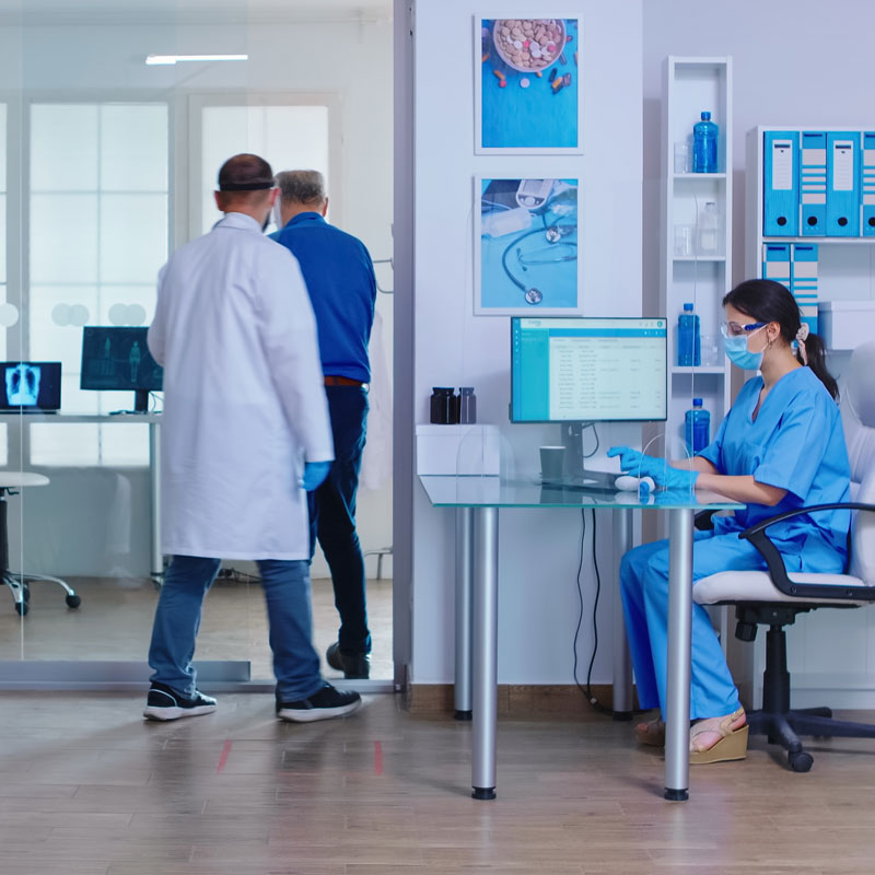 Patients wearing masks waiting in a medical clinic reception area.