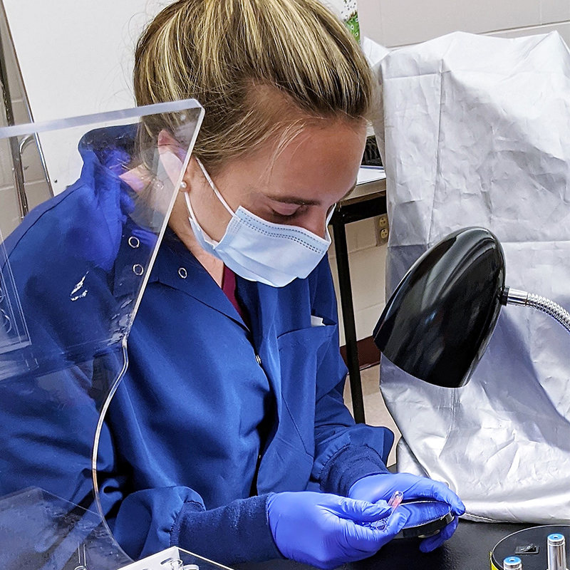 Student at Florence M. Cook School of Medical Laboratory Science wearing a mask and gloves.