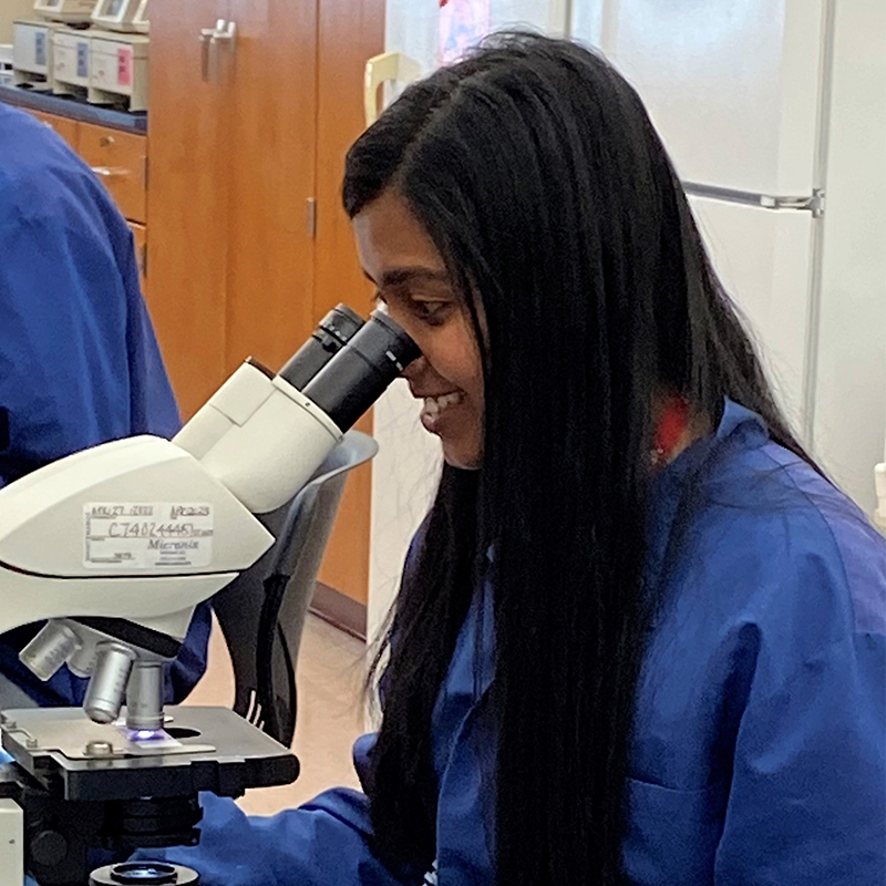 A female student looing into a microscope.
