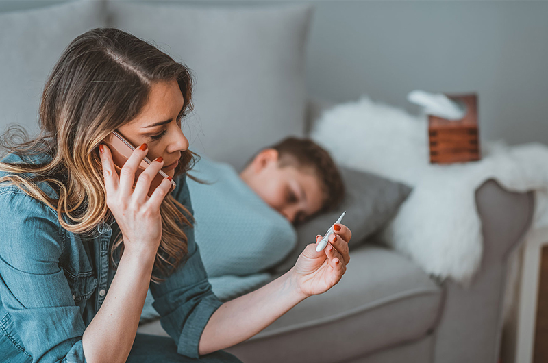 Mother sitting on child's bed talking on the phone.