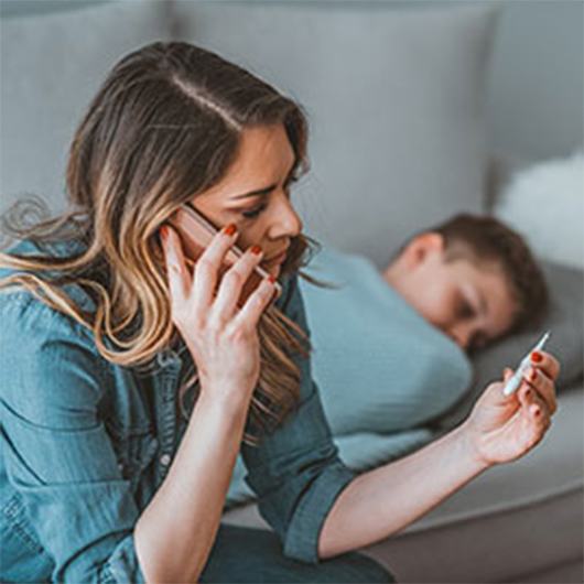 Mother sitting on child's bed talking on the phone.