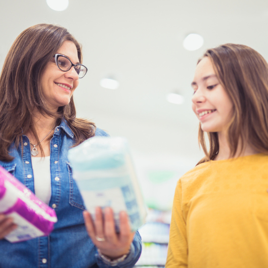 Mother and daughter choose sanitary pads to buy at the store.