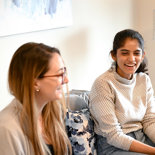 two young women on a couch laughing together