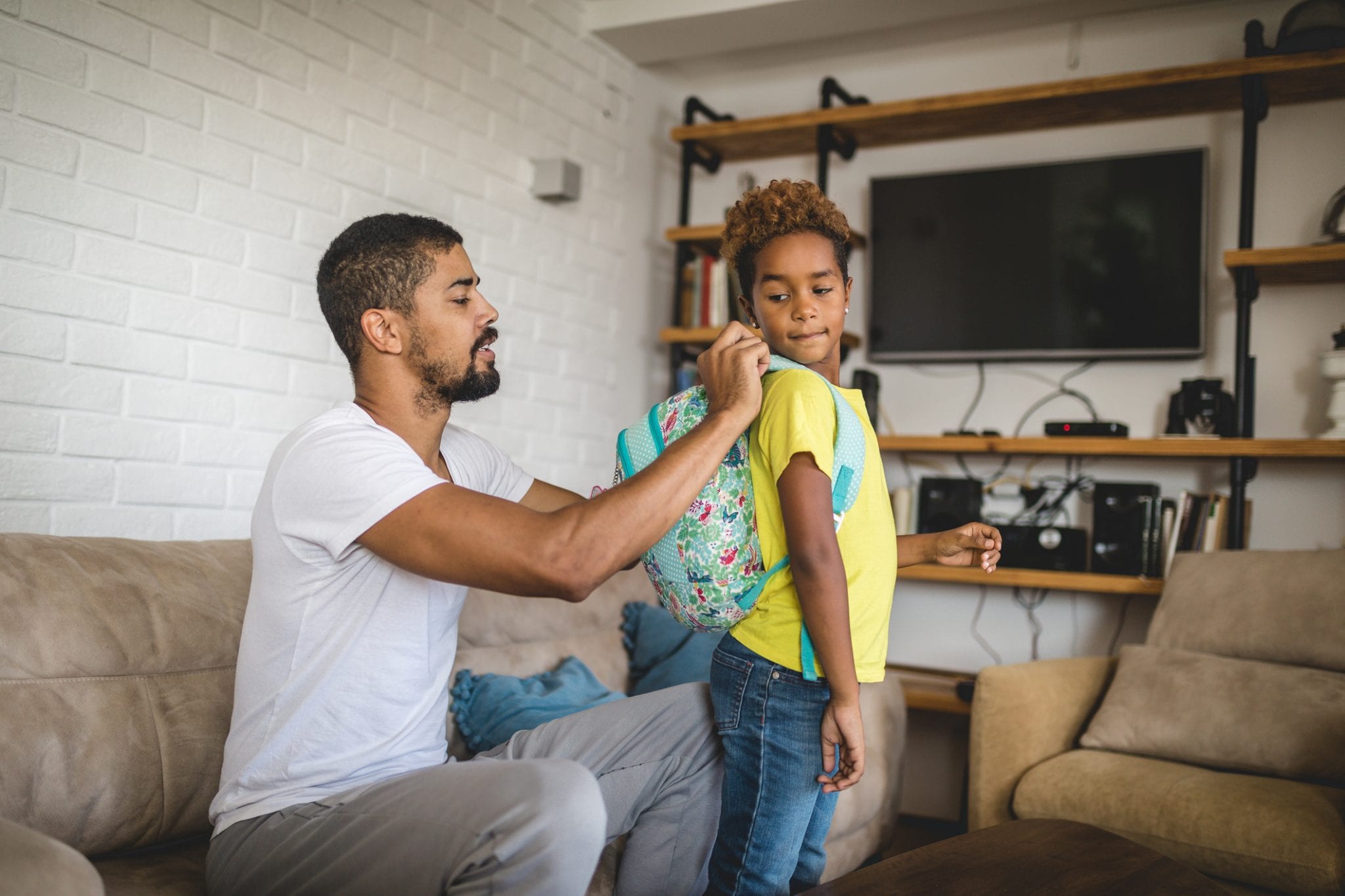Child putting on backpack