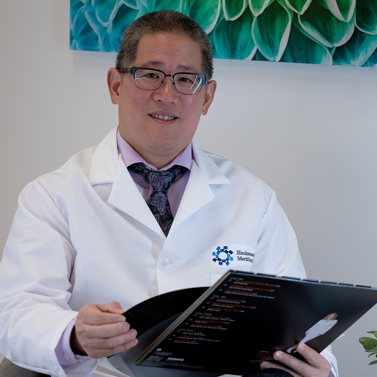 Michael Kuo, M.D., sitting in a chair, smiling, holding a vinyl record.