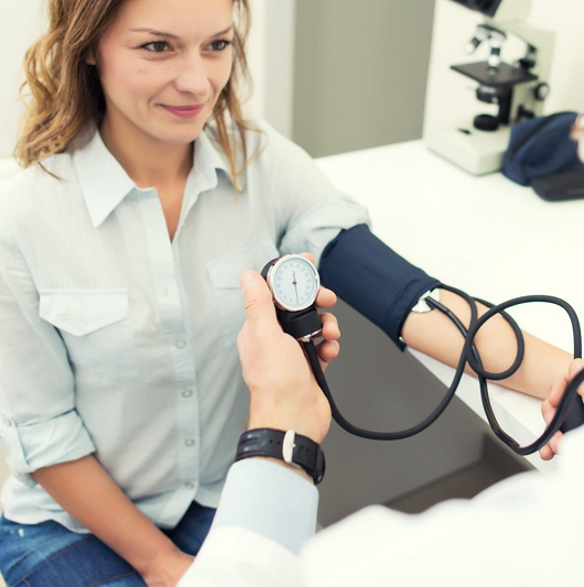 Woman having blood pressure taken by doctor in doctor's office.
