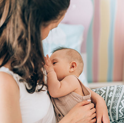 Mother breastfeeding her baby at home on the couch