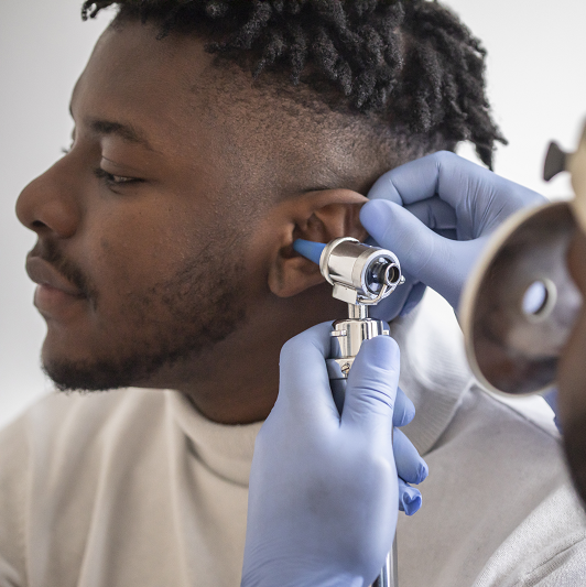 Close up of a male doctor carefully holding the ear of his patient to establish a clearer view of the inside of his ear, to see if he requires hearing aids