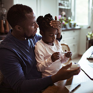 Father sits with daughter who is sick while on conference call with physician. Cold flu or RSV