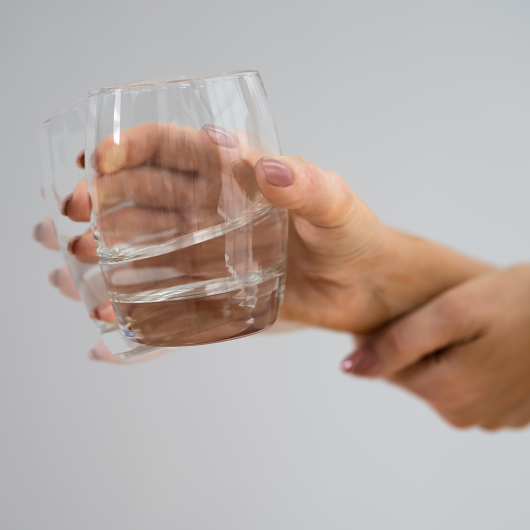 hand shaking from a tremor while holding a glass of water