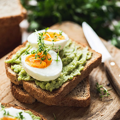 Healhy Breakfast Toast With Avocado, Boiled Egg On Wooden Cutting Board