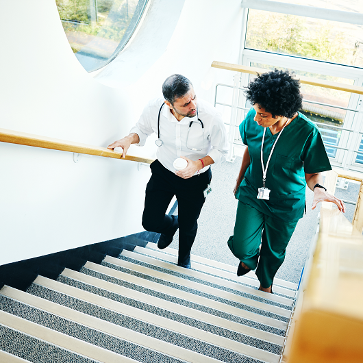 Two doctors walking on a staircase, having a conversation, in between cases in the hospital