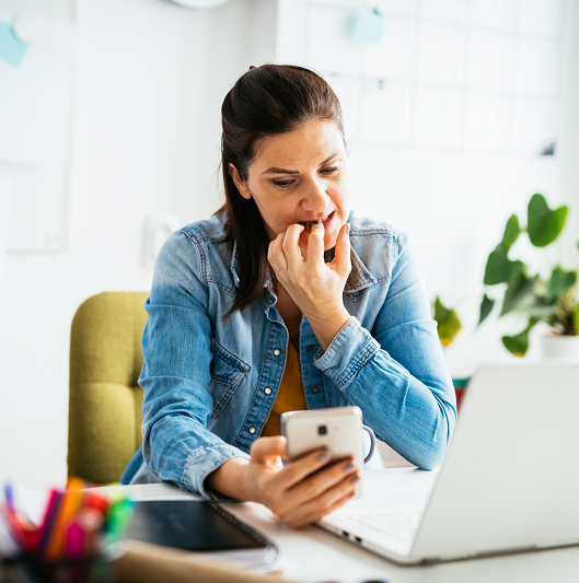 Anxious woman, biting her nails and working in office and using smart phone