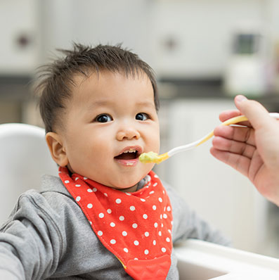 Asian baby being spoon fed some baby food