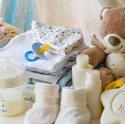 Newborn baby items including bottles, socks, teddy bear, burp clothes and diapers.