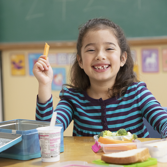 Young girl enjoying healthy snacks at school.