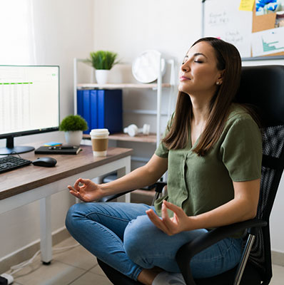 Young woman working from home taking a break during the work day to meditate and relax.