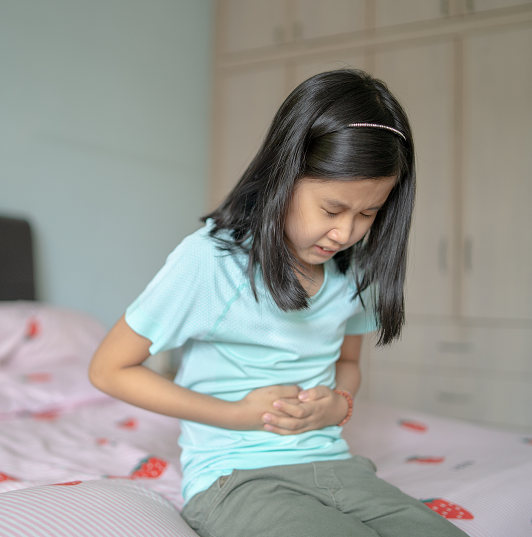 Young girl experiencing a stomach ache. Clenching her belly from digestive issues.