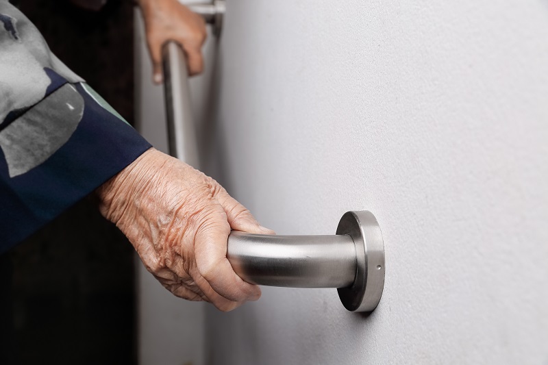 Elderly woman holding on handrail for safety walk steps in the home.