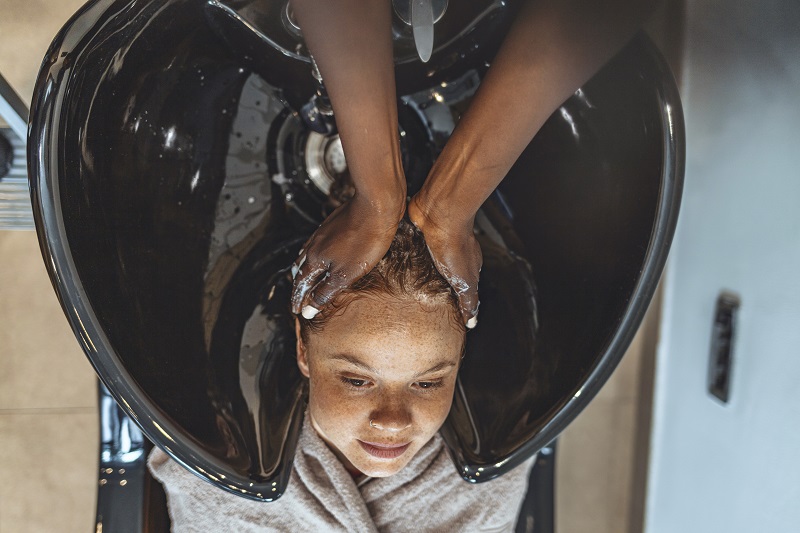 Young woman getting her hair done at a salon - chemical hair straightening.