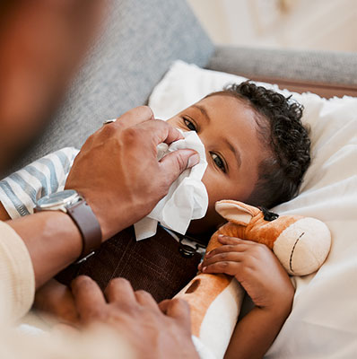 Parent taking care of sick child, blowing their nose. Cold remedies for children.