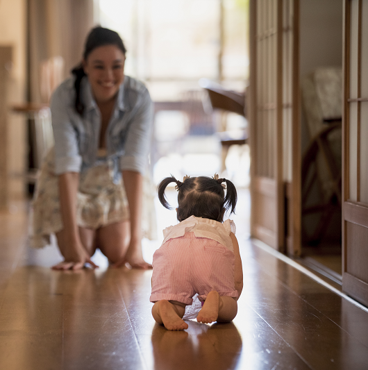 Baby crawling towards mother, meeting developmental milestones