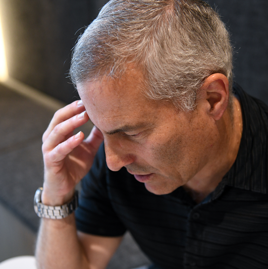 Man holding his forehead, managing stress and taking a moment to breathe.
