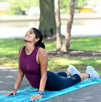 Young woman stretching in the park doing stretches for back pain.
