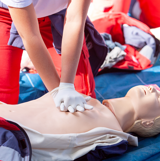 Woman performs chest compressions on a doll to teach CPR