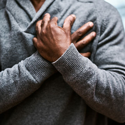 man clenches heart in pain, possibly heart attack or cardiac arrest