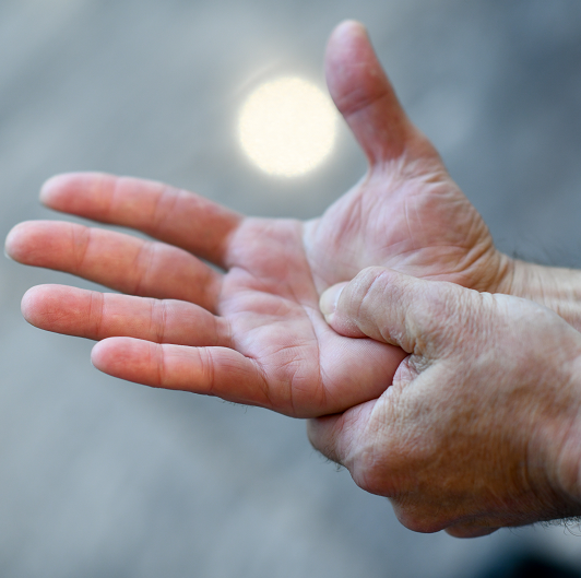 Man holding his hand feeling pain in the wrist and fingers, potentially carpal tunnel