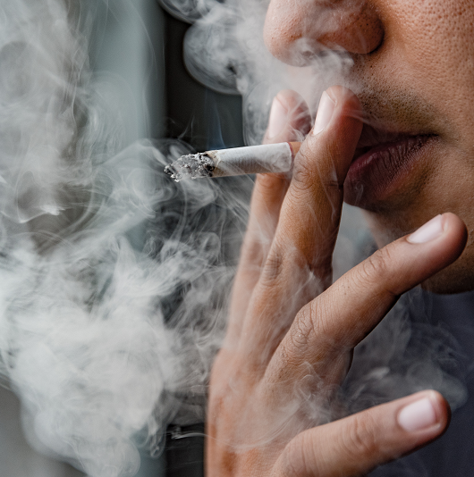 Close up of a woman's face smoking a cigarette and smoke coming out of her mouth