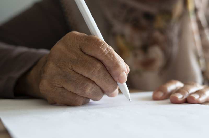 Person's hands as they take notes ahead of a doctor's appointment, writing down concerns