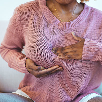 Woman feels her breasts on the outside of her sweater and notices a lump.