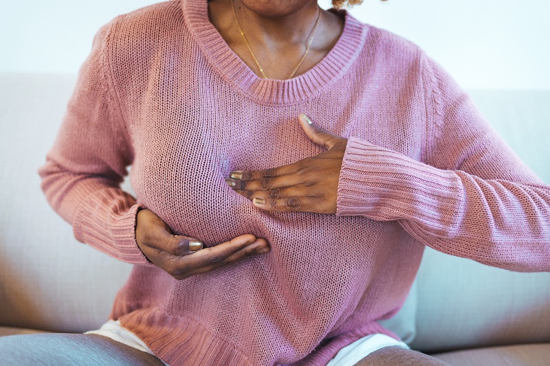 Woman feels her breasts on the outside of her sweater and notices a lump.