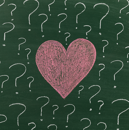 Chalk drawn heart with white question marks around it