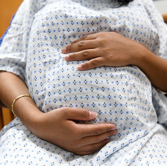 Pregnant mother holding her belly in the hospital before birth.