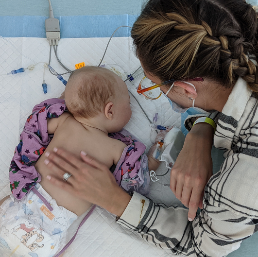 Katie looking over and comforting her hospitalized baby after surgery.